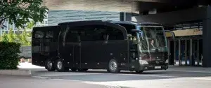 A big black bus with a driver in front of the frankfurt Airport waiting for VIP guests making an airport shuttle service.